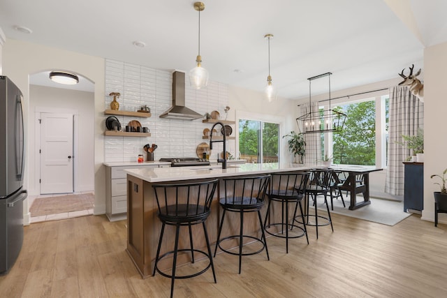 1819 Gloryfield Dr SW, Byron Center, MI 49315 - kitchen with wall chimney range hood, freestanding refrigerator, light countertops, tasteful backsplash, and light wood finished floors
