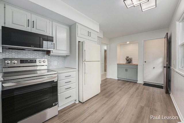 1043 Eastern Ave NE, Grand Rapids, MI 49503 - kitchen with stainless steel electric range, black microwave, freestanding refrigerator, light wood-style flooring, and decorative backsplash