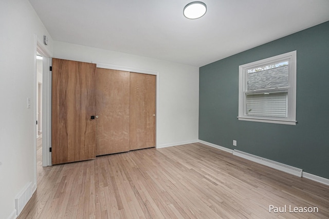 1043 Eastern Ave NE, Grand Rapids, MI 49503 - unfurnished bedroom featuring a baseboard radiator, wood finished floors, a closet, and baseboards