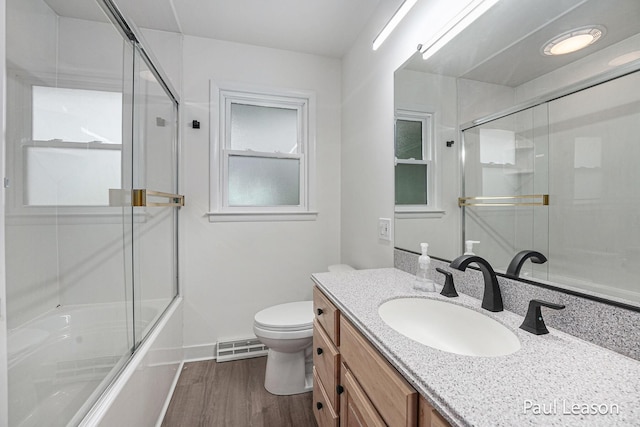 1043 Eastern Ave NE, Grand Rapids, MI 49503 - bathroom featuring toilet, vanity, combined bath / shower with glass door, wood finished floors, and baseboards
