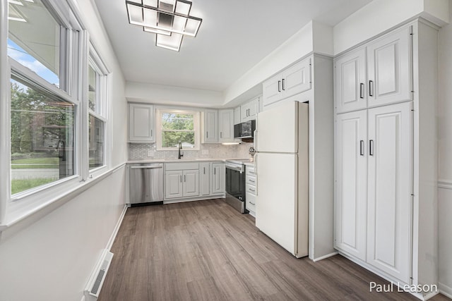 1043 Eastern Ave NE, Grand Rapids, MI 49503 - kitchen with stainless steel appliances, wood finished floors, light countertops, tasteful backsplash, and white cabinets