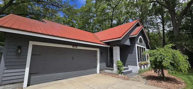 4447 Deer Creek Dr, Norton Shores, MI 49441 - view of front of property featuring metal roof, an attached garage, and concrete driveway