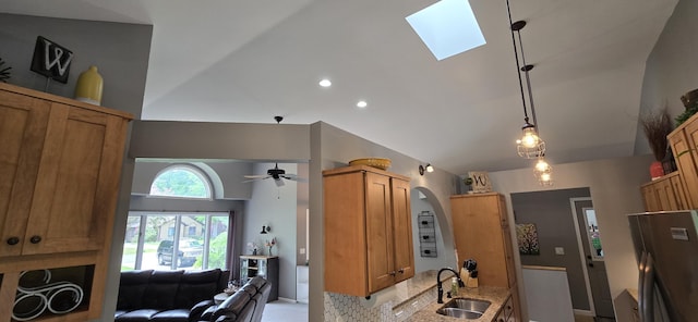 4447 Deer Creek Dr, Norton Shores, MI 49441 - kitchen with a sink, a skylight, light stone counters, a ceiling fan, and brown cabinets