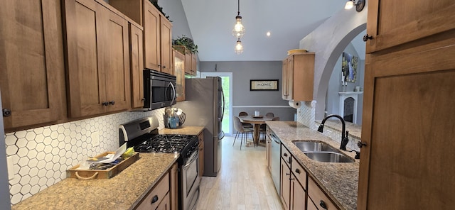 4447 Deer Creek Dr, Norton Shores, MI 49441 - kitchen with appliances with stainless steel finishes, a sink, decorative backsplash, vaulted ceiling, and arched walkways