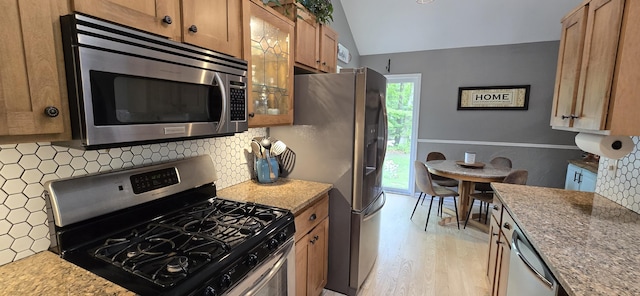 4447 Deer Creek Dr, Norton Shores, MI 49441 - kitchen with appliances with stainless steel finishes, light wood finished floors, backsplash, vaulted ceiling, and brown cabinetry