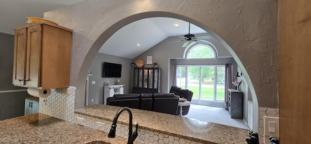 4447 Deer Creek Dr, Norton Shores, MI 49441 - kitchen featuring a ceiling fan, vaulted ceiling, arched walkways, open floor plan, and light stone countertops