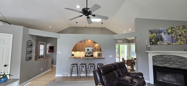4447 Deer Creek Dr, Norton Shores, MI 49441 - living area with a fireplace, a ceiling fan, light wood-style flooring, lofted ceiling, and recessed lighting