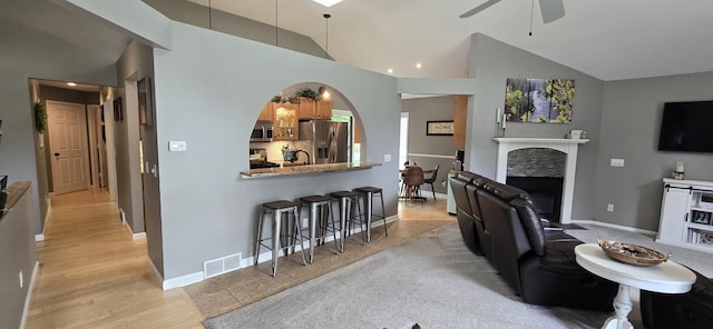 4447 Deer Creek Dr, Norton Shores, MI 49441 - living area featuring a ceiling fan, vaulted ceiling, a fireplace, baseboards, and recessed lighting