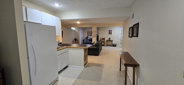4447 Deer Creek Dr, Norton Shores, MI 49441 - kitchen with freestanding refrigerator, white cabinetry, open floor plan, a peninsula, and a textured ceiling