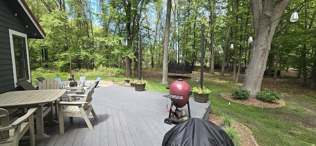 4447 Deer Creek Dr, Norton Shores, MI 49441 - wooden terrace with a trampoline, outdoor dining space, and view of scattered trees