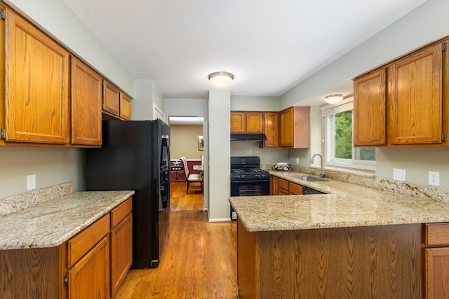 24609 Redwing Dr, Novi, MI 48374 - kitchen with black appliances, a sink, light wood finished floors, a peninsula, and under cabinet range hood