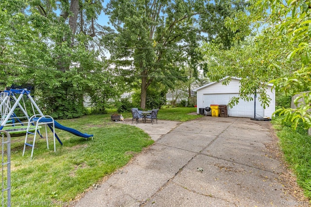 34642 Elm St, Wayne, MI 48184 - view of green lawn with a detached garage, a playground, an outbuilding, and an outdoor fire pit