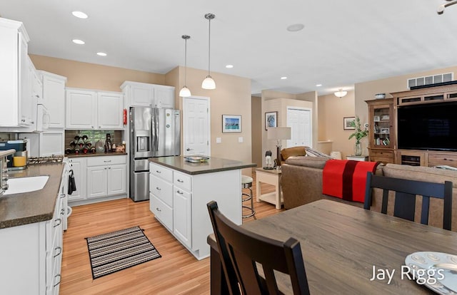 5702 Copper Sands Run Unit 101, Fruitport, MI 49415 - kitchen with stainless steel fridge, dark countertops, open floor plan, white cabinetry, and light wood-type flooring