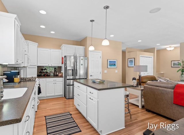 5702 Copper Sands Run Unit 101, Fruitport, MI 49415 - kitchen featuring appliances with stainless steel finishes, dark countertops, a kitchen bar, light wood finished floors, and open floor plan
