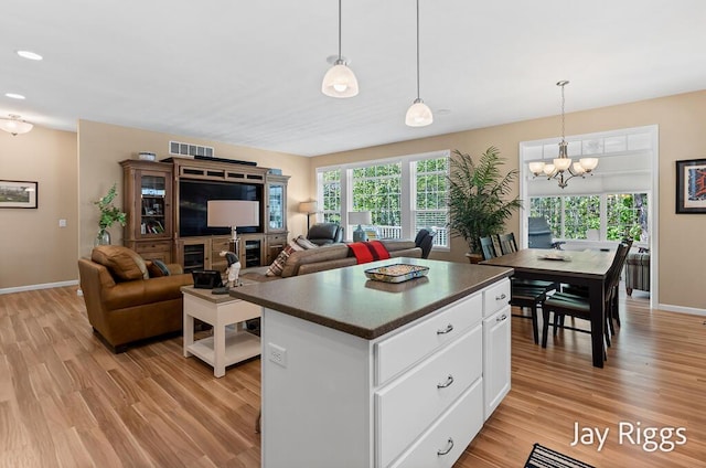 5702 Copper Sands Run Unit 101, Fruitport, MI 49415 - kitchen featuring dark countertops, light wood-style flooring, a chandelier, and white cabinetry