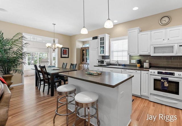 5702 Copper Sands Run Unit 101, Fruitport, MI 49415 - kitchen featuring white appliances, dark countertops, a sink, a chandelier, and white cabinets