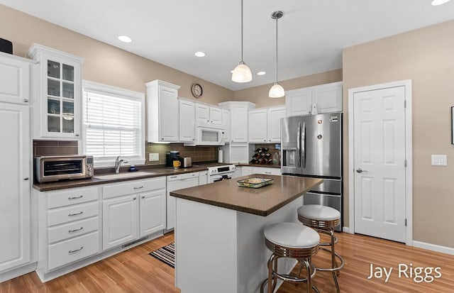 5702 Copper Sands Run Unit 101, Fruitport, MI 49415 - kitchen featuring white appliances, a sink, dark countertops, light wood-type flooring, and recessed lighting