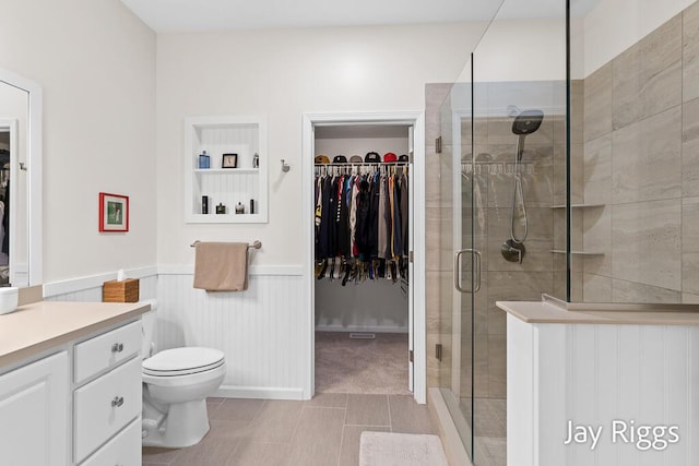 5702 Copper Sands Run Unit 101, Fruitport, MI 49415 - bathroom with vanity, a walk in closet, toilet, a shower stall, and wainscoting