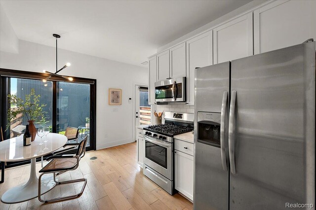 3303 Cochrane, Detroit, MI 48208 - kitchen with stainless steel appliances, a chandelier, tasteful backsplash, light wood finished floors, and white cabinetry