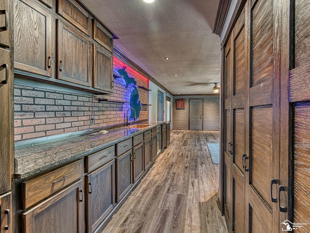 22933 Monterey Dr, Woodhaven, MI 48183 - kitchen with a sink, dark wood finished floors, a textured ceiling, dark stone countertops, and dark brown cabinets