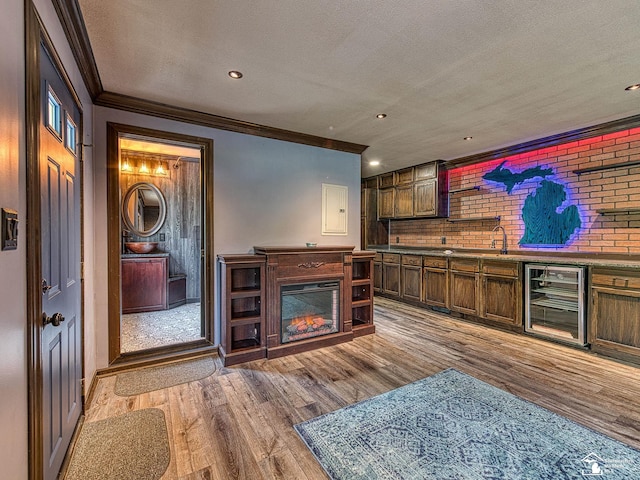 22933 Monterey Dr, Woodhaven, MI 48183 - living room featuring wine cooler, crown molding, light wood-style floors, a textured ceiling, and a glass covered fireplace