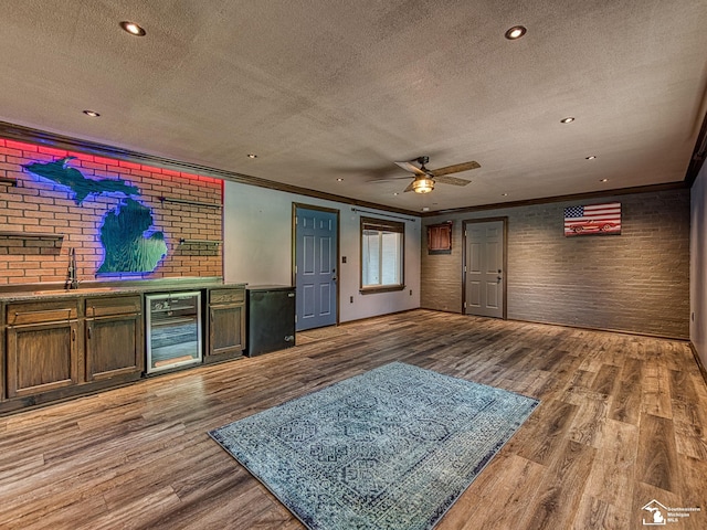 22933 Monterey Dr, Woodhaven, MI 48183 - unfurnished living room featuring wine cooler, a textured ceiling, brick wall, wood finished floors, and crown molding