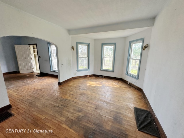 5207 S Whiteville Rd, Mount Pleasant, MI 48858 - empty room featuring arched walkways, wood-type flooring, and baseboards