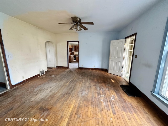 5207 S Whiteville Rd, Mount Pleasant, MI 48858 - unfurnished living room featuring hardwood / wood-style floors, ceiling fan, arched walkways, and baseboards