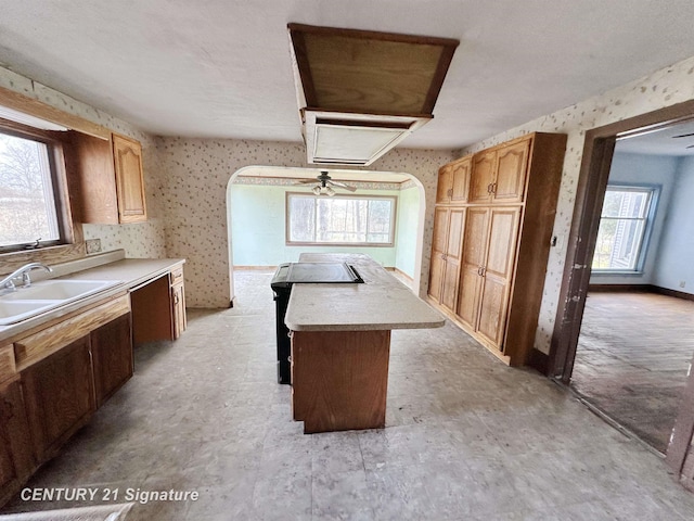 5207 S Whiteville Rd, Mount Pleasant, MI 48858 - kitchen featuring a sink, a kitchen island, wallpapered walls, light countertops, and dishwashing machine