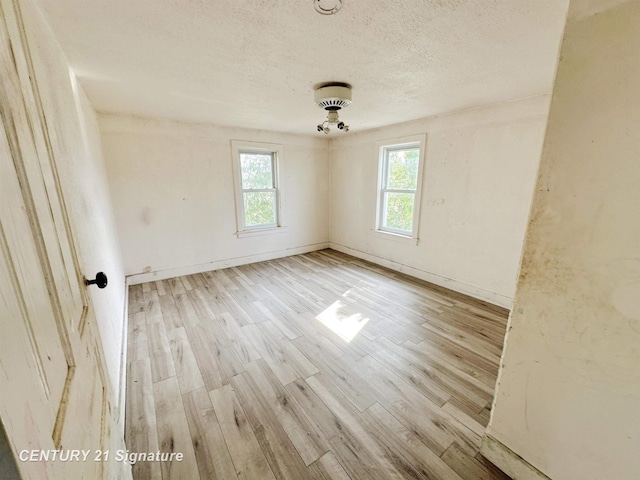 5207 S Whiteville Rd, Mount Pleasant, MI 48858 - unfurnished room featuring healthy amount of natural light, a textured ceiling, wood finished floors, and baseboards