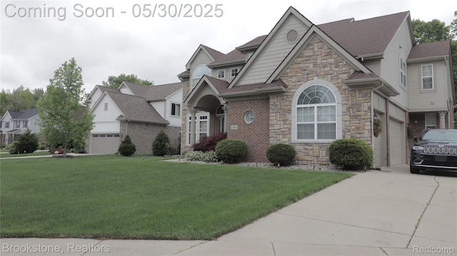 13961 Cobblestone Creek Dr, Belleville, MI 48111 - view of front of home with stone siding, a front lawn, roof with shingles, driveway, and an attached garage