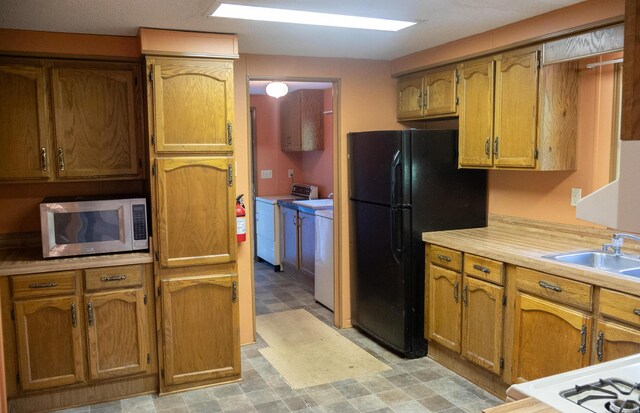 6340 Warren Woods Rd, Three Oaks, MI 49128 - kitchen featuring stainless steel microwave, washing machine and dryer, light countertops, light floors, and freestanding refrigerator