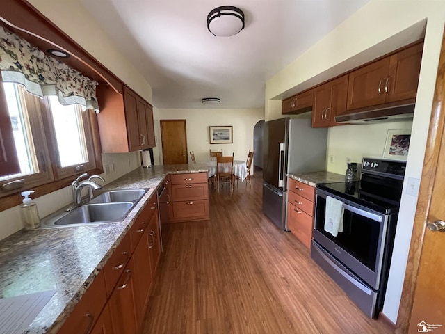 8263 Westwood St, Ida, MI 48140 - kitchen with appliances with stainless steel finishes, a sink, under cabinet range hood, arched walkways, and dark wood finished floors