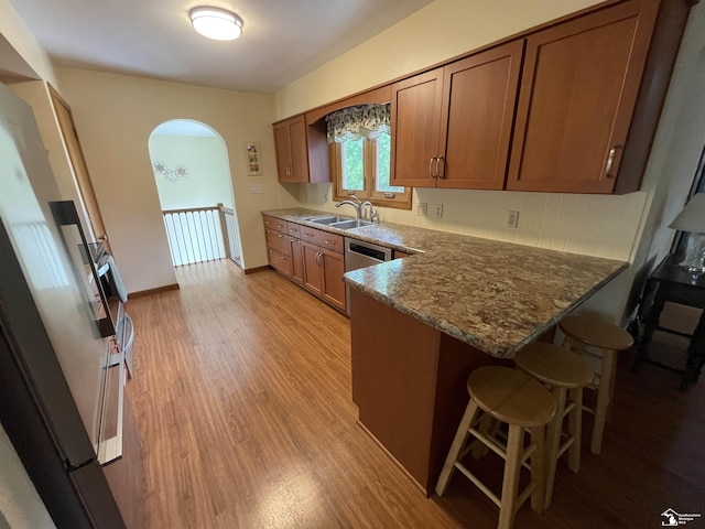 8263 Westwood St, Ida, MI 48140 - kitchen with a sink, arched walkways, a peninsula, and brown cabinetry