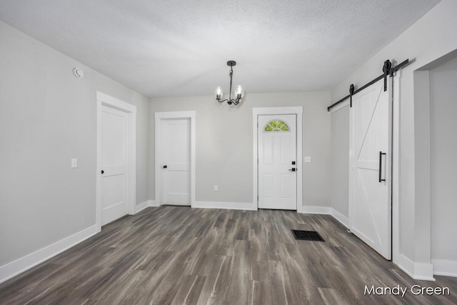 536 E Grant St, Sheridan, MI 48884 - foyer entrance featuring a barn door, dark wood-style flooring, baseboards, a textured ceiling, and a chandelier