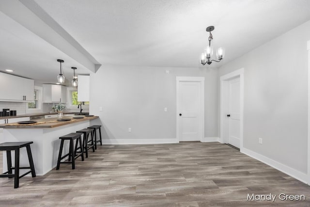 536 E Grant St, Sheridan, MI 48884 - kitchen featuring white cabinets, a breakfast bar, baseboards, and light wood-style flooring