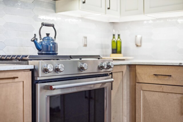616 S Elm St, Three Oaks, MI 49128 - kitchen featuring high end stainless steel range, decorative backsplash, light stone counters, and light brown cabinetry