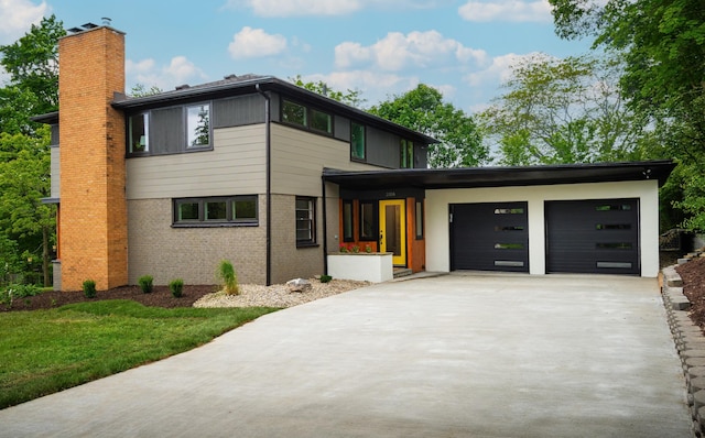 2316 Brockman Blvd, Ann Arbor, MI 48104 - view of front of home featuring concrete driveway, an attached garage, a chimney, brick siding, and a front lawn