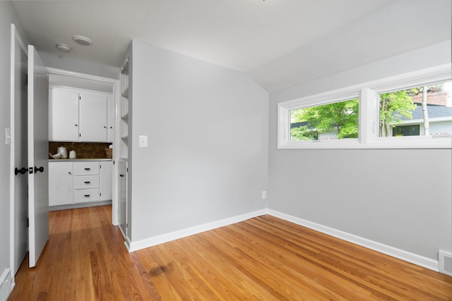 2316 Brockman Blvd, Ann Arbor, MI 48104 - unfurnished bedroom with light wood finished floors, baseboards, multiple windows, and vaulted ceiling