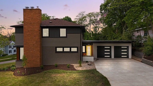 2316 Brockman Blvd, Ann Arbor, MI 48104 - contemporary house with concrete driveway, a chimney, an attached garage, and a lawn