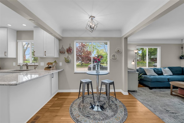 1104 James K Blvd, Pontiac, MI 48341 - kitchen with a sink, light wood-style flooring, white cabinetry, light stone countertops, and healthy amount of natural light