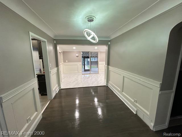 1042 Drexel St, Dearborn, MI 48128 - hallway with a decorative wall, arched walkways, wainscoting, and dark wood-style floors