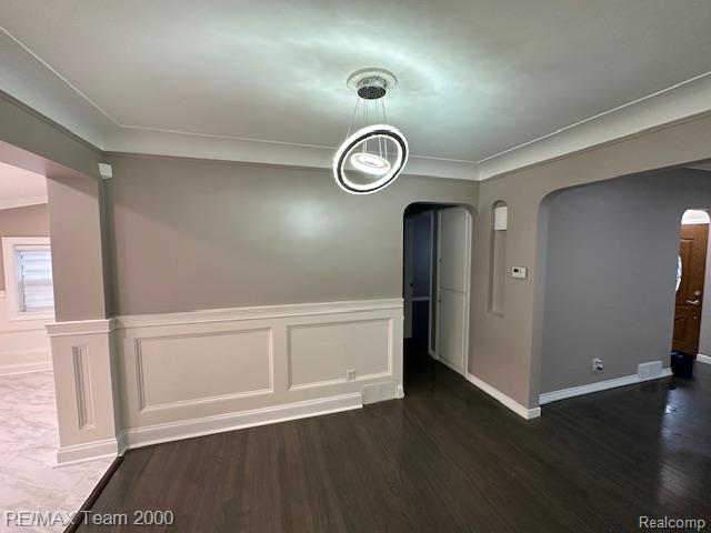 1042 Drexel St, Dearborn, MI 48128 - unfurnished dining area with arched walkways, wood finished floors, crown molding, a wainscoted wall, and a decorative wall
