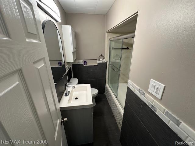 1042 Drexel St, Dearborn, MI 48128 - full bath featuring toilet, vanity, enclosed tub / shower combo, tile walls, and a wainscoted wall