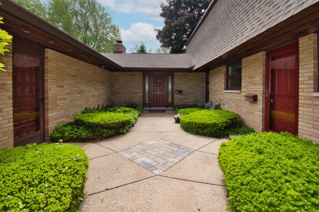 2727 S Lakeshore Dr Unit F-24, Saint Joseph, MI 49085 - view of exterior entry featuring a chimney, brick siding, and roof with shingles