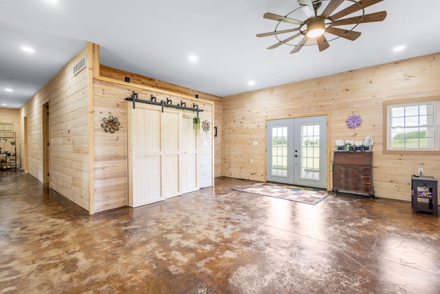 17495 Bison Trl, White Pigeon, MI 49099 - unfurnished living room featuring wooden walls, french doors, finished concrete floors, ceiling fan, and a barn door