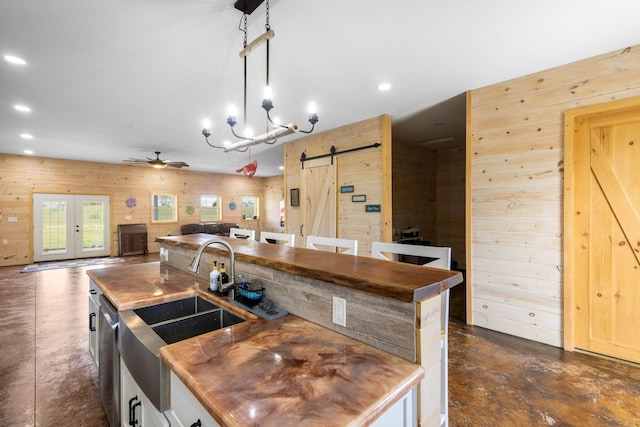 17495 Bison Trl, White Pigeon, MI 49099 - kitchen with a barn door, wood walls, concrete flooring, dishwasher, and a sink