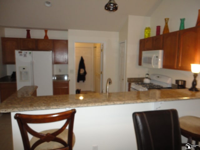 36111 Traditions Dr, Westland, MI 48185 - kitchen featuring white appliances, a peninsula, light stone counters, and a kitchen breakfast bar