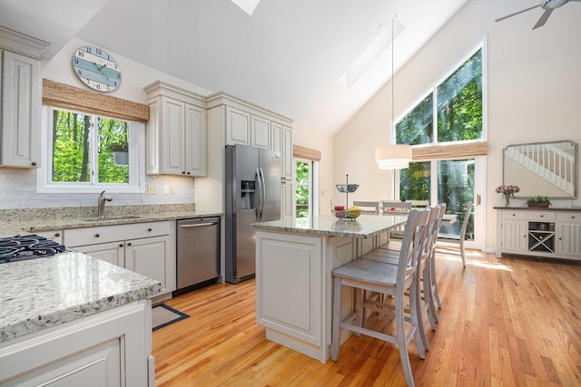 12215 Dunes Rd, Sawyer, MI 49125 - kitchen featuring stainless steel appliances, high vaulted ceiling, light wood-style flooring, a breakfast bar area, and a sink