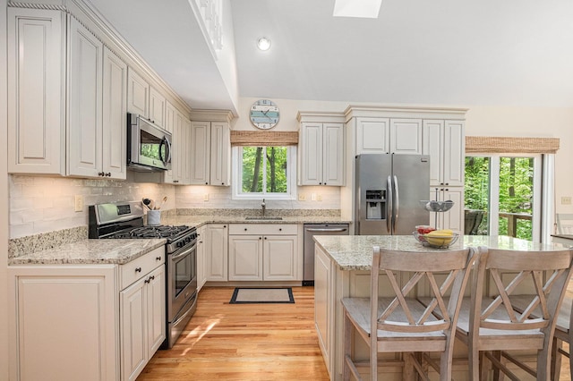 12215 Dunes Rd, Sawyer, MI 49125 - kitchen with appliances with stainless steel finishes, a sink, healthy amount of natural light, light wood-style flooring, and vaulted ceiling